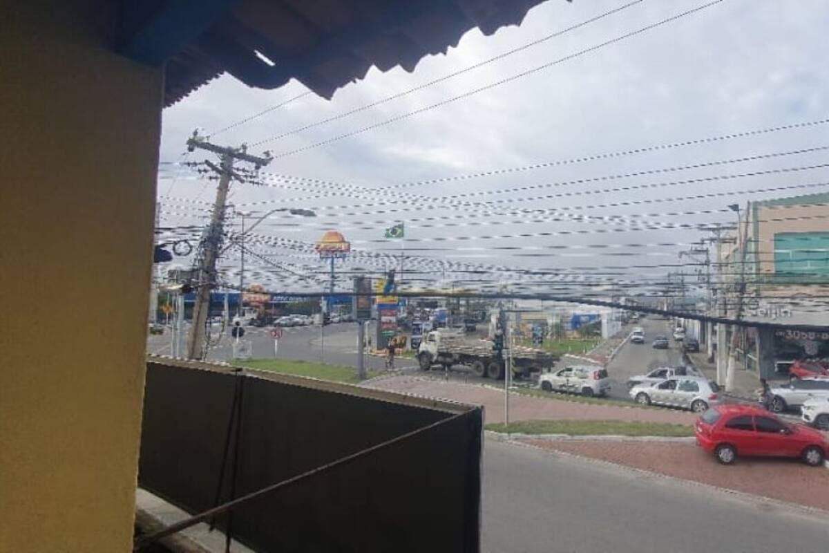 Une vue de rue avec des voitures garées, une station-service et un bâtiment orné d’une enseigne rouge.