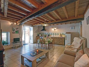 Un salon chaleureux avec un plafond en bois, un coin repas avec une table et des chaises, et une cuisine équipée d’un four à micro-ondes et d’un évier.