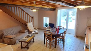 Ein gemütliches Wohnzimmer mit einer Holztreppe, einem Esstisch mit Stühlen, einer Couch und einem Couchtisch.