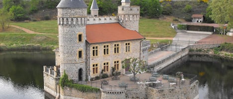 A castle-like structure with a moat, stone walls, and a red-tiled roof.
