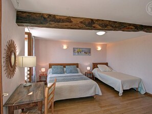 Une chambre avec un plafond en bois, deux lits, un bureau et une chaise.