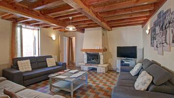 A cozy living room with a fireplace, sofas, a coffee table, and a television.