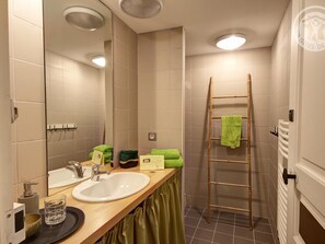 A bathroom with a wooden vanity, a mirror, a sink, and a shower area with a bamboo ladder.