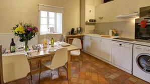 Una cocina compacta con comedor, lavadora y ventana con persianas.