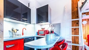 Una cocina compacta con electrodomésticos modernos, un refrigerador rojo y una pared de acento de madera.