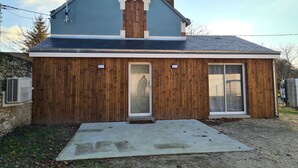 Une maison à deux étages, avec un toit en pente, un revêtement en bois et une cheminée.