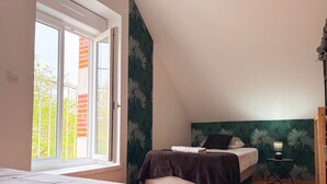 Une chambre avec deux lits, une fenêtre et une vue sur un immeuble en briques.