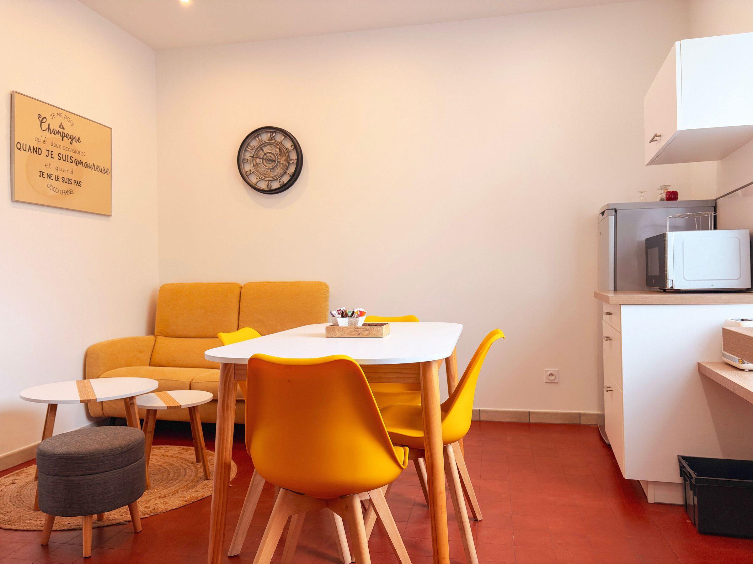 A compact living space with a dining area, a sofa, a small table, and a microwave.