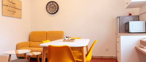 A compact living space with a dining area, a sofa, a small table, and a microwave.