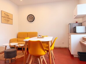 A compact living space with a dining area, a sofa, a small table, and a microwave. - Charming Cottage Near Beauval Zoo & Loire Castles - Private Courtyard & Bike Access (La Vernelle)