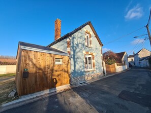 Une maison à deux étages, avec une clôture en bois, une cheminée et une allée pavée.