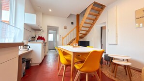 Une cuisine moderne avec un coin repas, un escalier en bois et une vue sur la rue.
