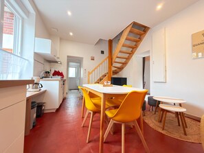 Une cuisine moderne avec un coin repas, un escalier en bois et une vue sur la rue.