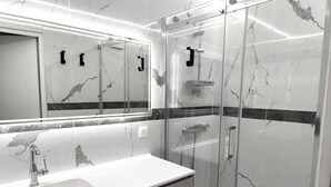 A modern bathroom with a marble vanity, a glass-enclosed shower, and a large mirror. - Savoyard duplex for 6 in Méribel center with wifi (Méribel)