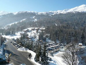 A snow-covered mountain town with buildings, parked cars, and a clear sky.