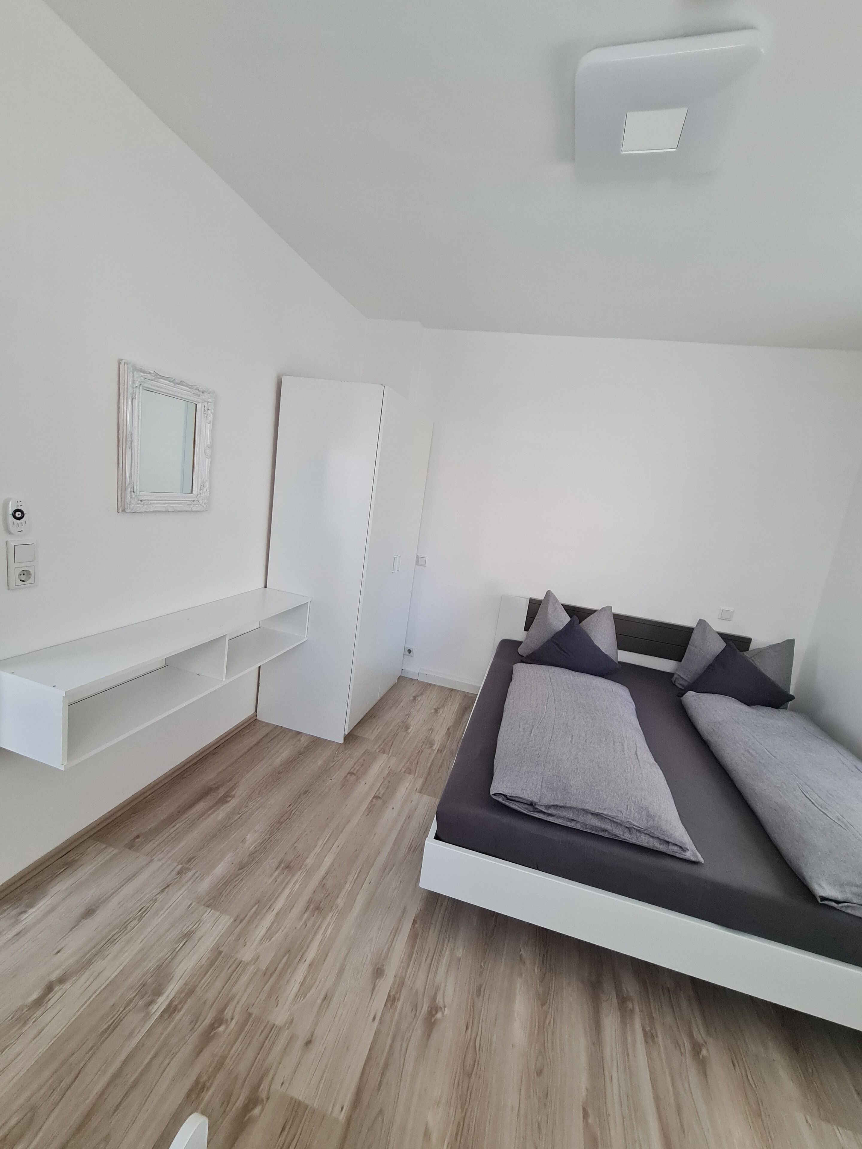 Une chambre à coucher au style minimaliste, avec un lit, des tables de chevet et une armoire.