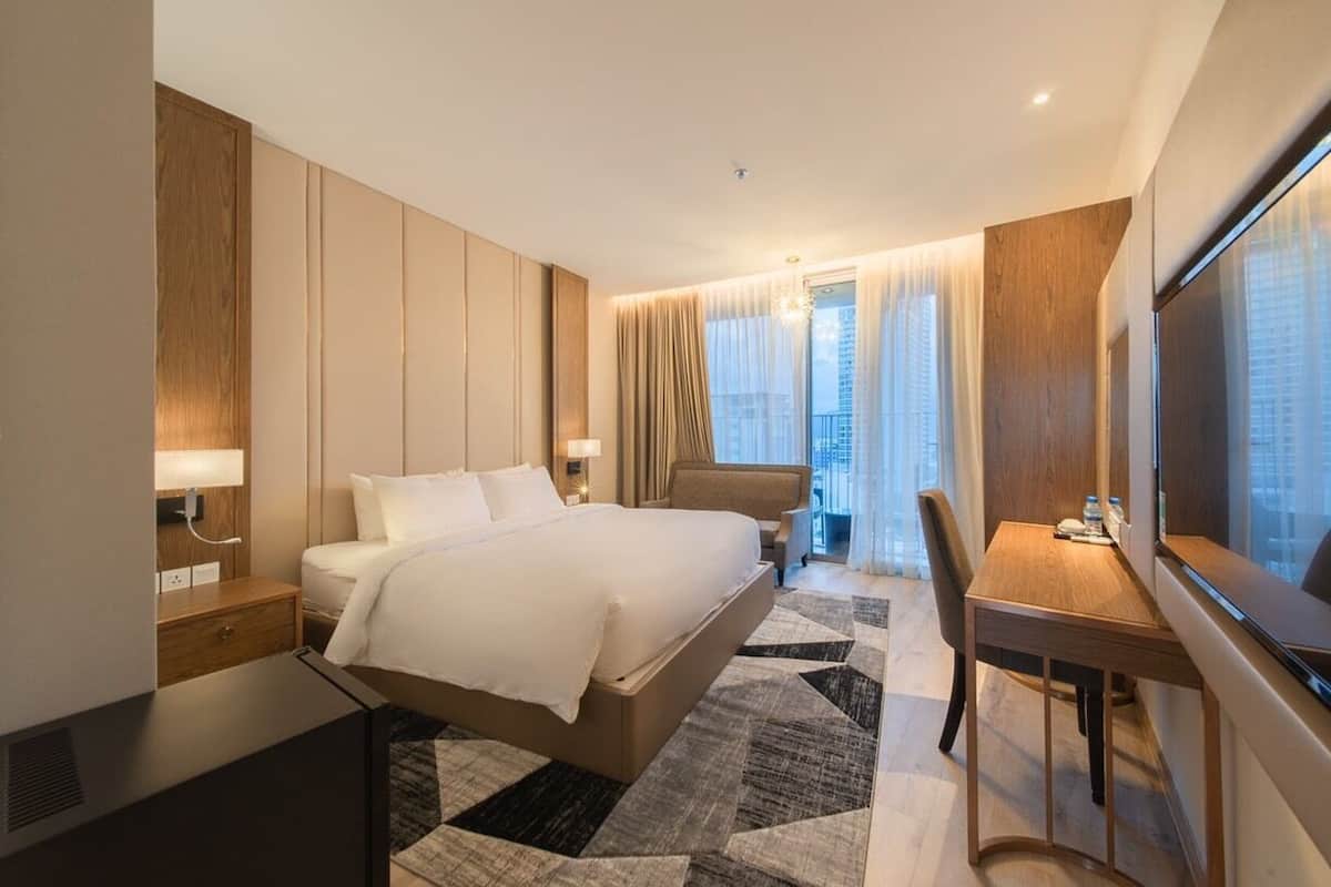 A modern hotel room with a large bed, a desk, and a TV.