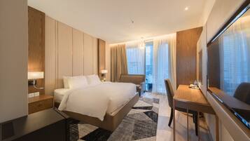 A modern hotel room with a large bed, a desk, and a TV.