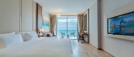 Un cuarto de hotel con una cama grande, un escritorio con una silla, un televisor y un balcón con vista al mar.