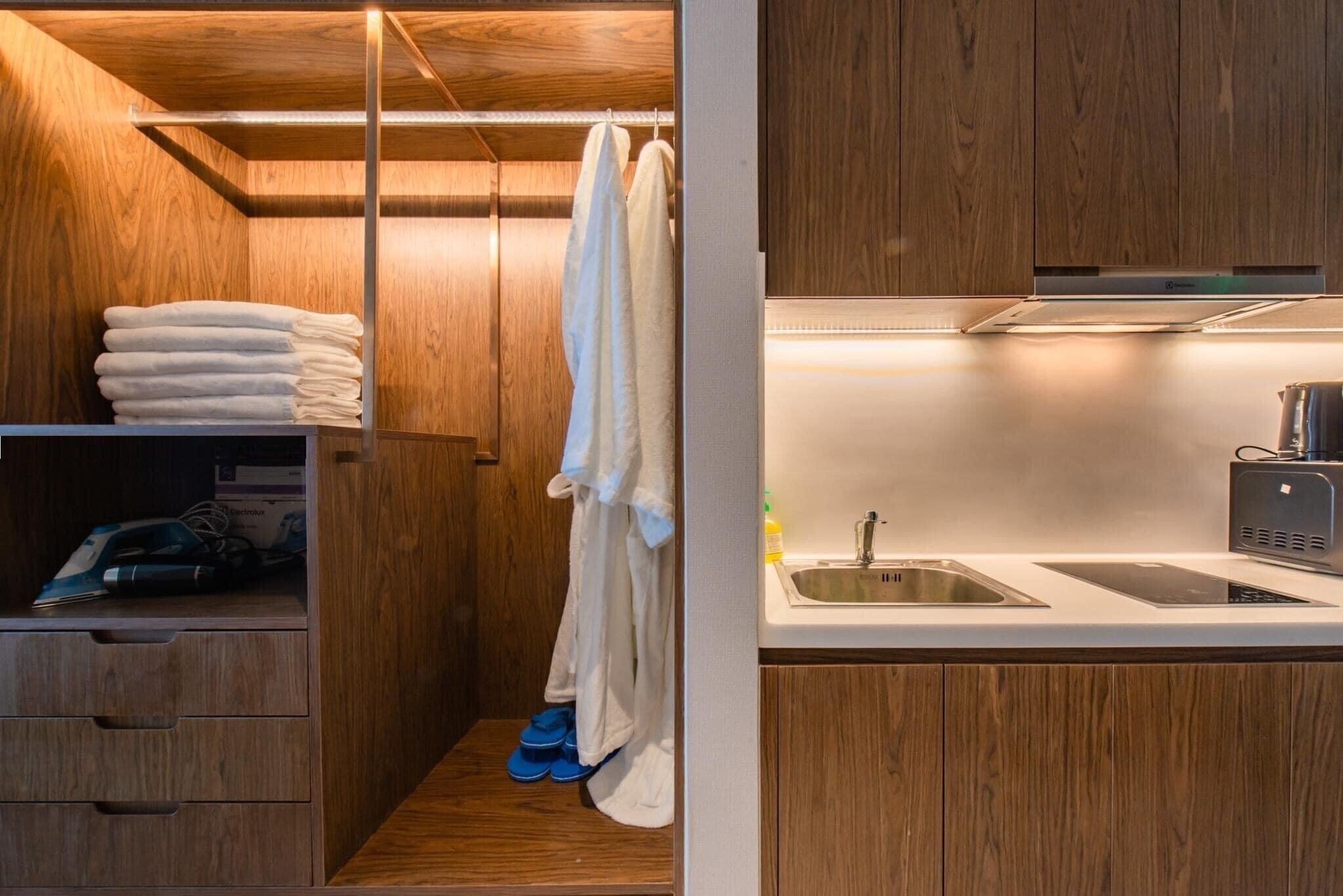 Un bagno moderno con mobili in legno, cabina doccia integrata e un piano d'appoggio bianco con lavandino e macchina da caffè.