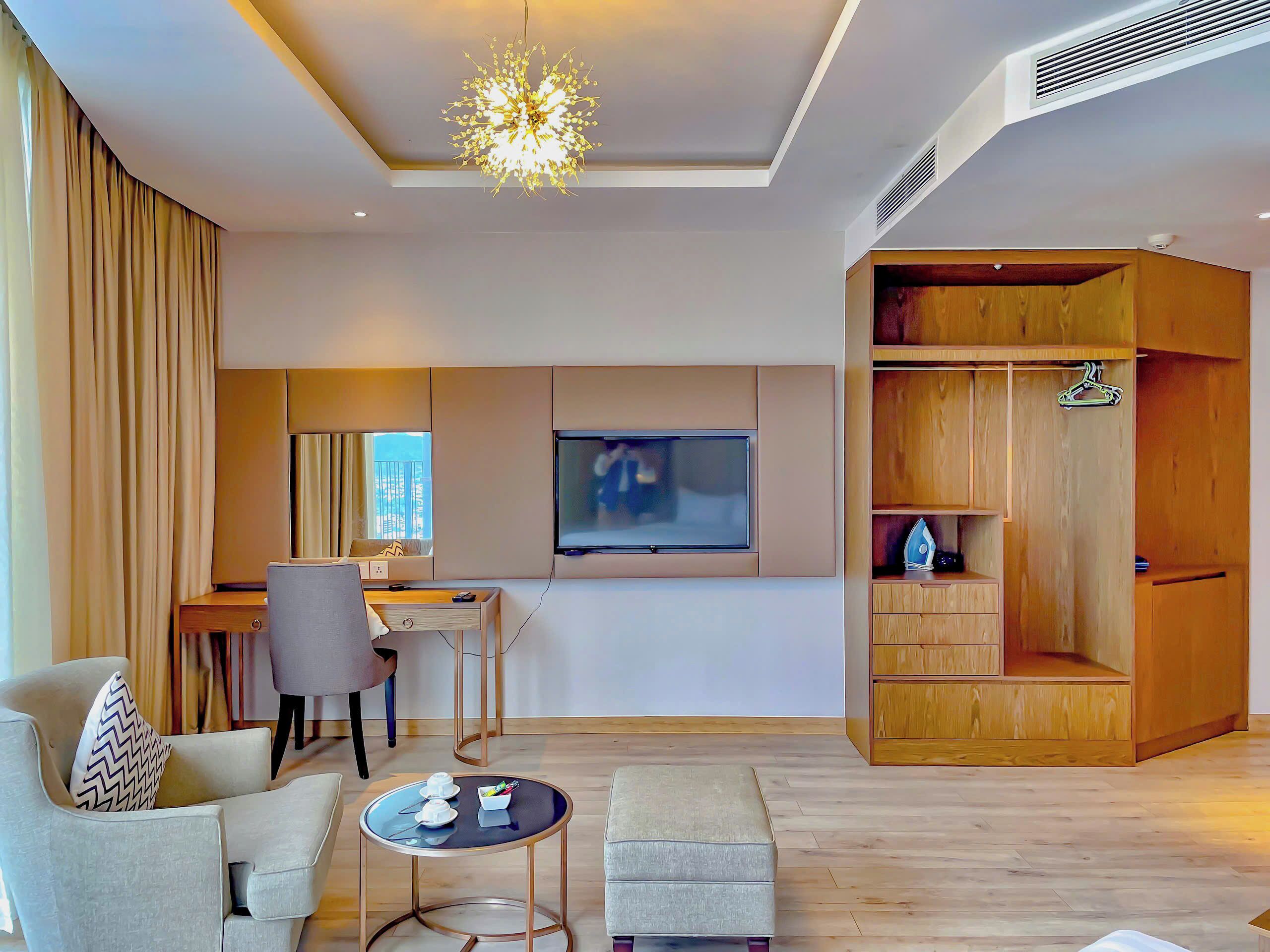 Un salon moderne comprenant un coin repas, un téléviseur fixé au mur et une armoire en bois.