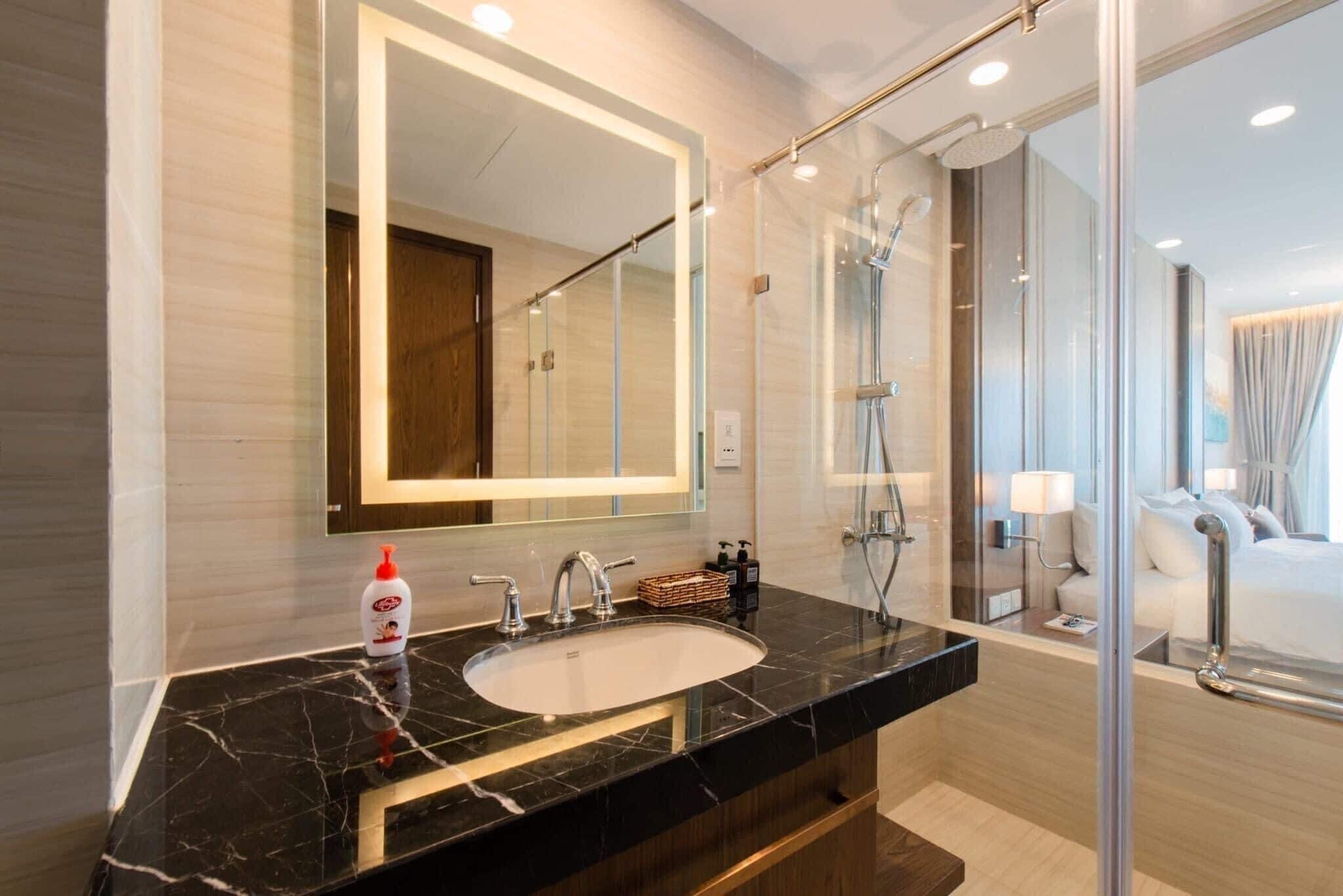 A modern bathroom with a marble sink, a large mirror, and a glass shower enclosure.