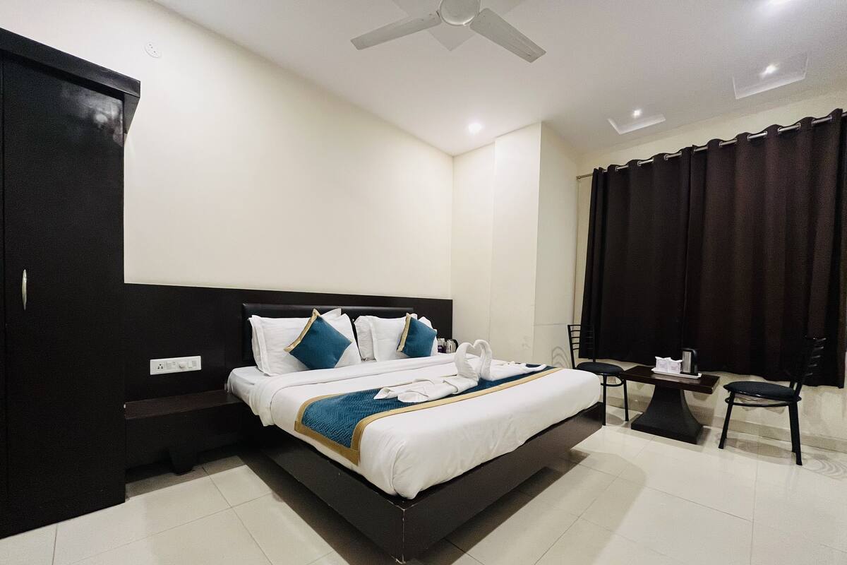 Quarto de hotel com cama, guarda-roupa, escrivaninha e uma cadeira.
