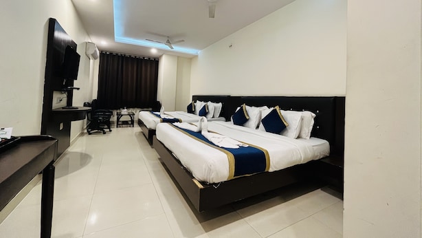 A hotel room with a large bed, a desk, a chair, a TV, and a ceiling fan. - Hotel City Heritage Haridwar (Haridwar)