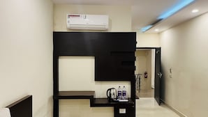 A hotel room with a black console table, a white air conditioner, and a small trash bin. - Hotel City Heritage Haridwar (Haridwar)