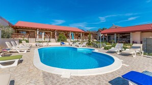 Un espace piscine doté de chaises longues et d’une terrasse carrelée en pierre.