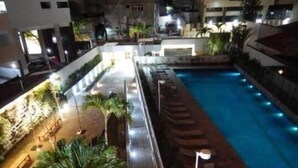 An outdoor swimming pool with surrounding palm trees and a paved walkway. - my way s flats (Fortaleza)