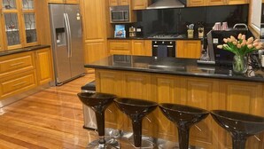 Una cocina moderna con armarios de madera, electrodomésticos de acero inoxidable y una isla central con taburetes de bar.