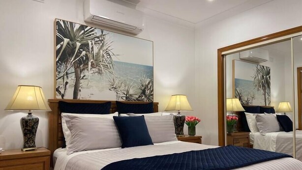 Habitación de hotel con una cama grande, dos mesitas de noche, un espejo y un equipo de aire acondicionado.