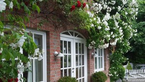 Une maison en briques avec des fenêtres à cadre blanc, un banc blanc et un chemin pavé.