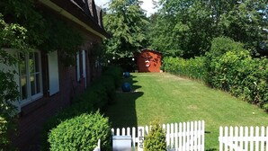 Une maison avec un toit de chaume, une allée pavée et une clôture blanche en bois.