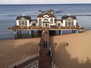 Un muelle que se adentra en el mar con un edificio al final, que cuenta con múltiples ventanas y una entrada central.