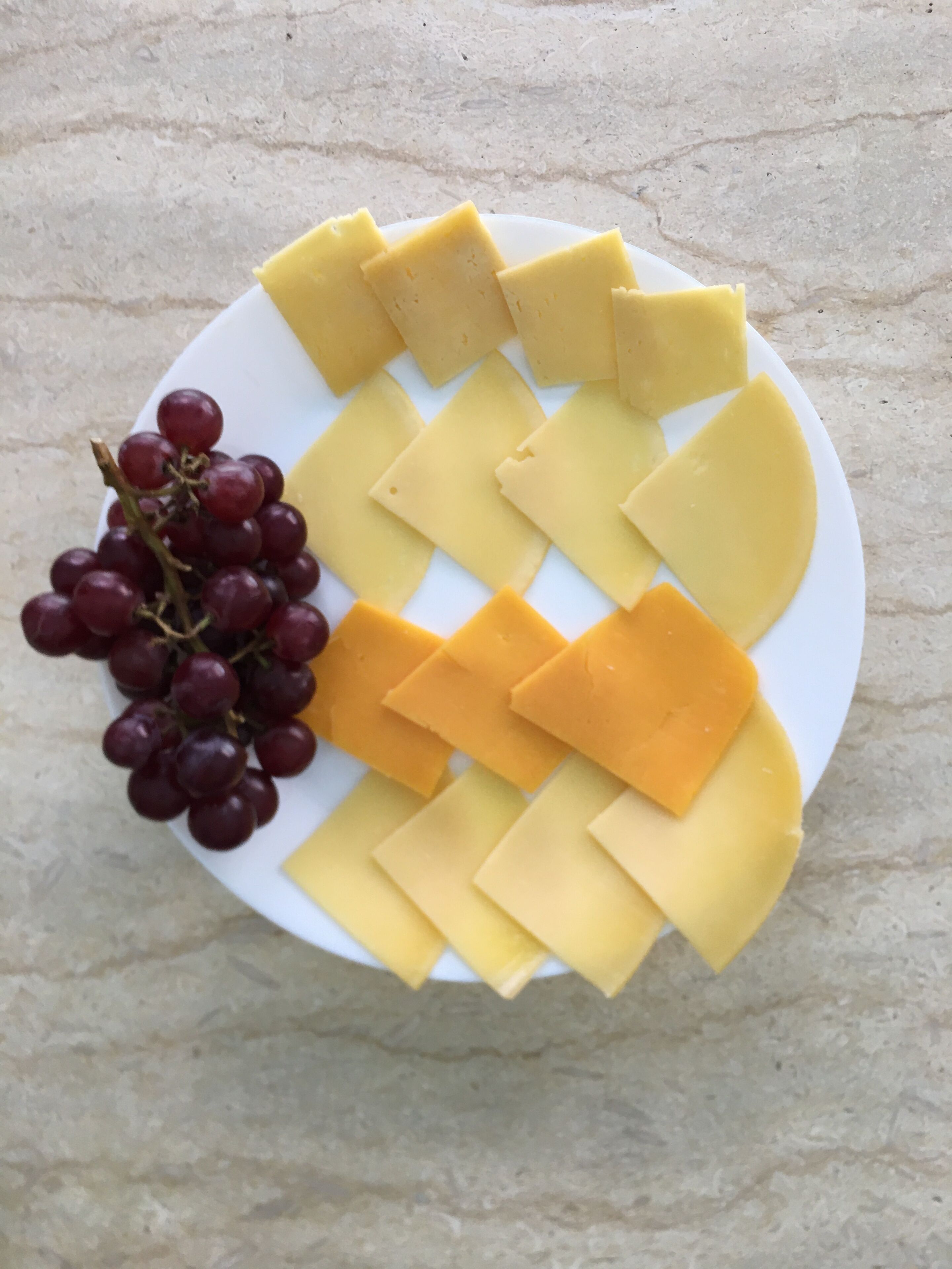 A plate with cheese and grapes.