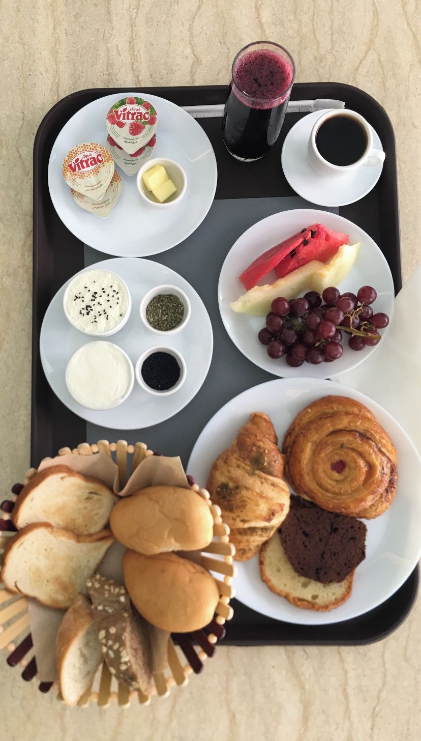 Ein Tablett mit verschiedenen Speisen, darunter Joghurt, Honig, Brot und Gebäck.