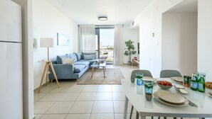 Una sala de estar moderna con un sofá, una mesa de centro y una mesa de comedor dispuesta con platos, vasos y un frutero.