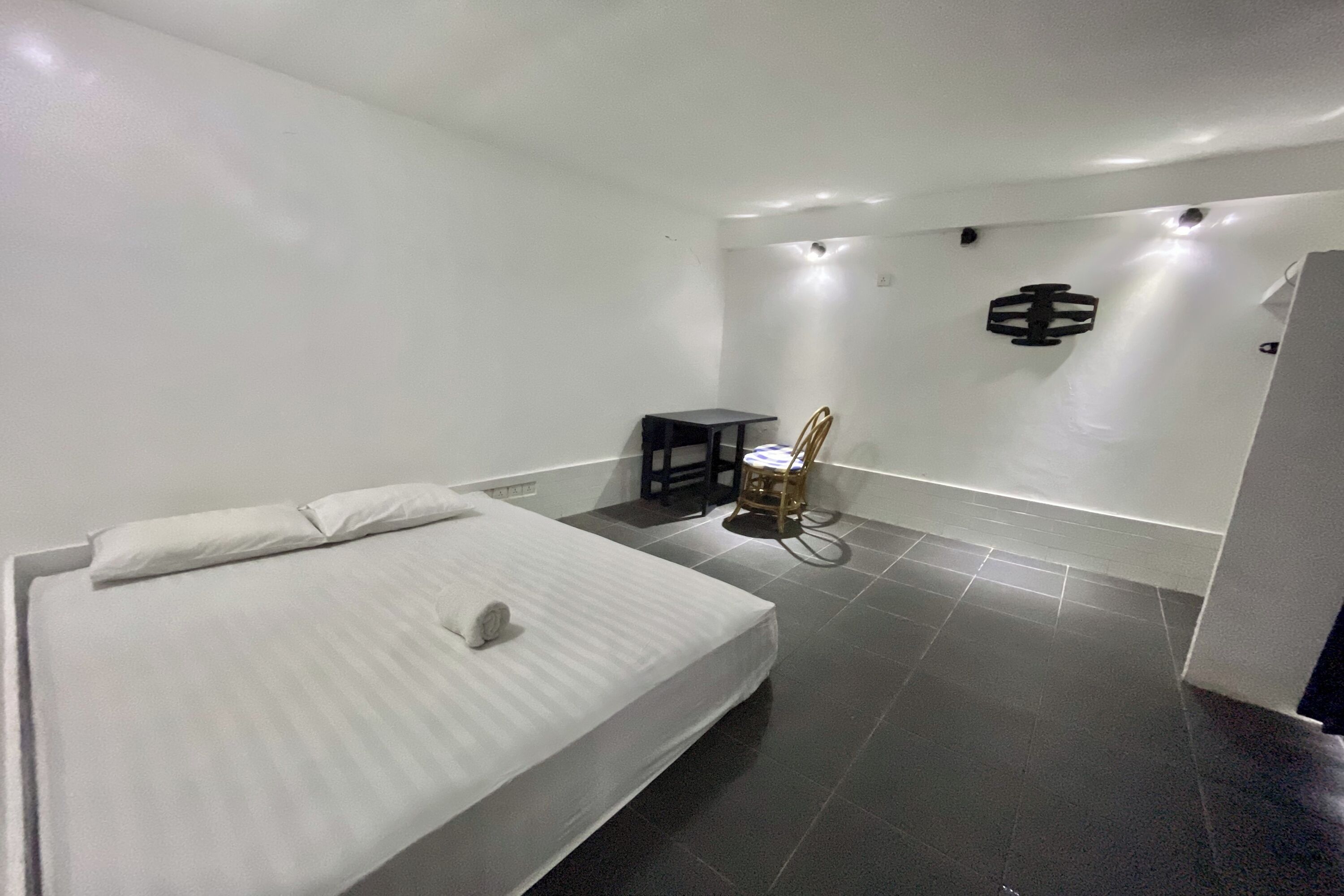 A modern hotel room with a neatly made bed, a small table, and a chair.