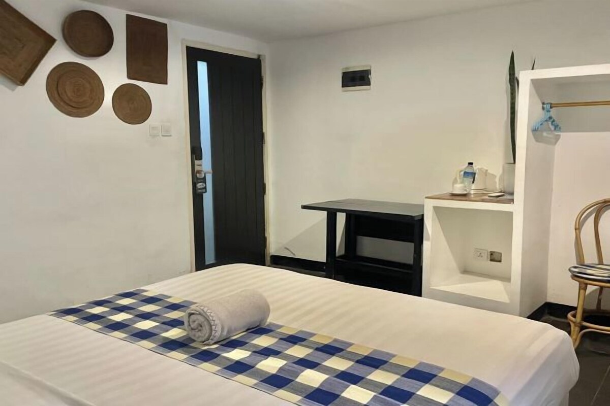 Una habitación de hotel con una cama, un escritorio, una silla y un armario.