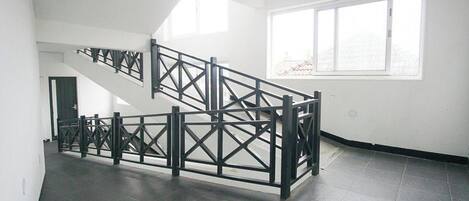 A staircase with a black metal railing in a room with white walls and a large window.