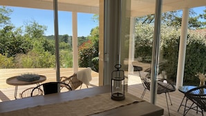 Een modern terras buiten, met een houten tafel, stoelen en een glazen lantaarn.
