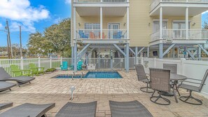 A pool area with lounge chairs, a small pool, and a two-story building with balconies.