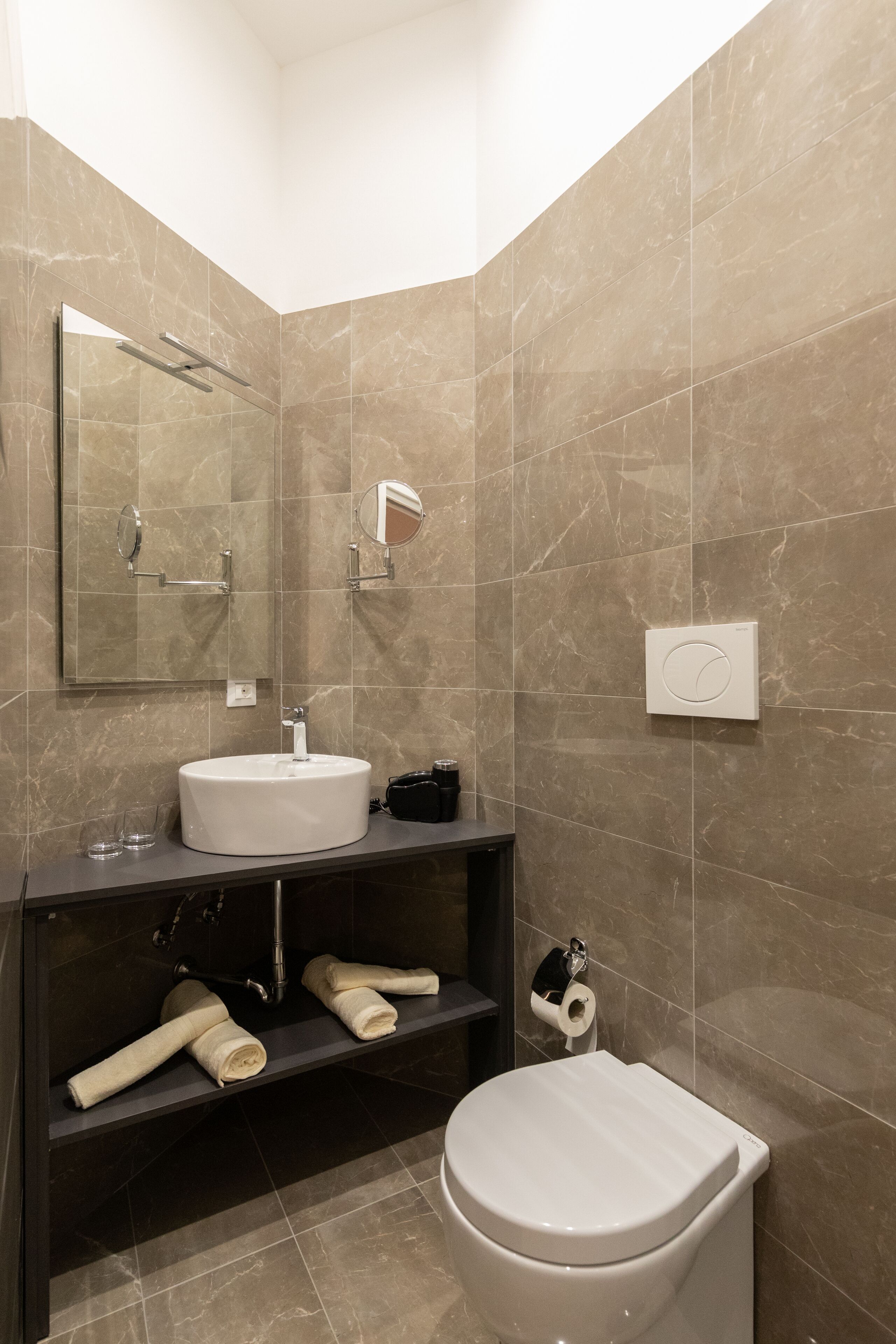 Un baño moderno con lavamanos blanco, espejo, toallero y retrete.