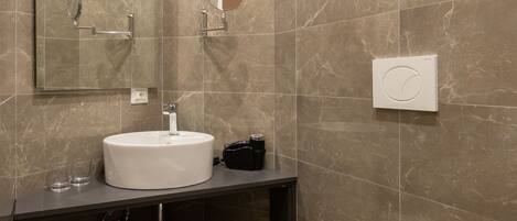 Un baño moderno con lavamanos blanco, espejo, toallero y retrete.