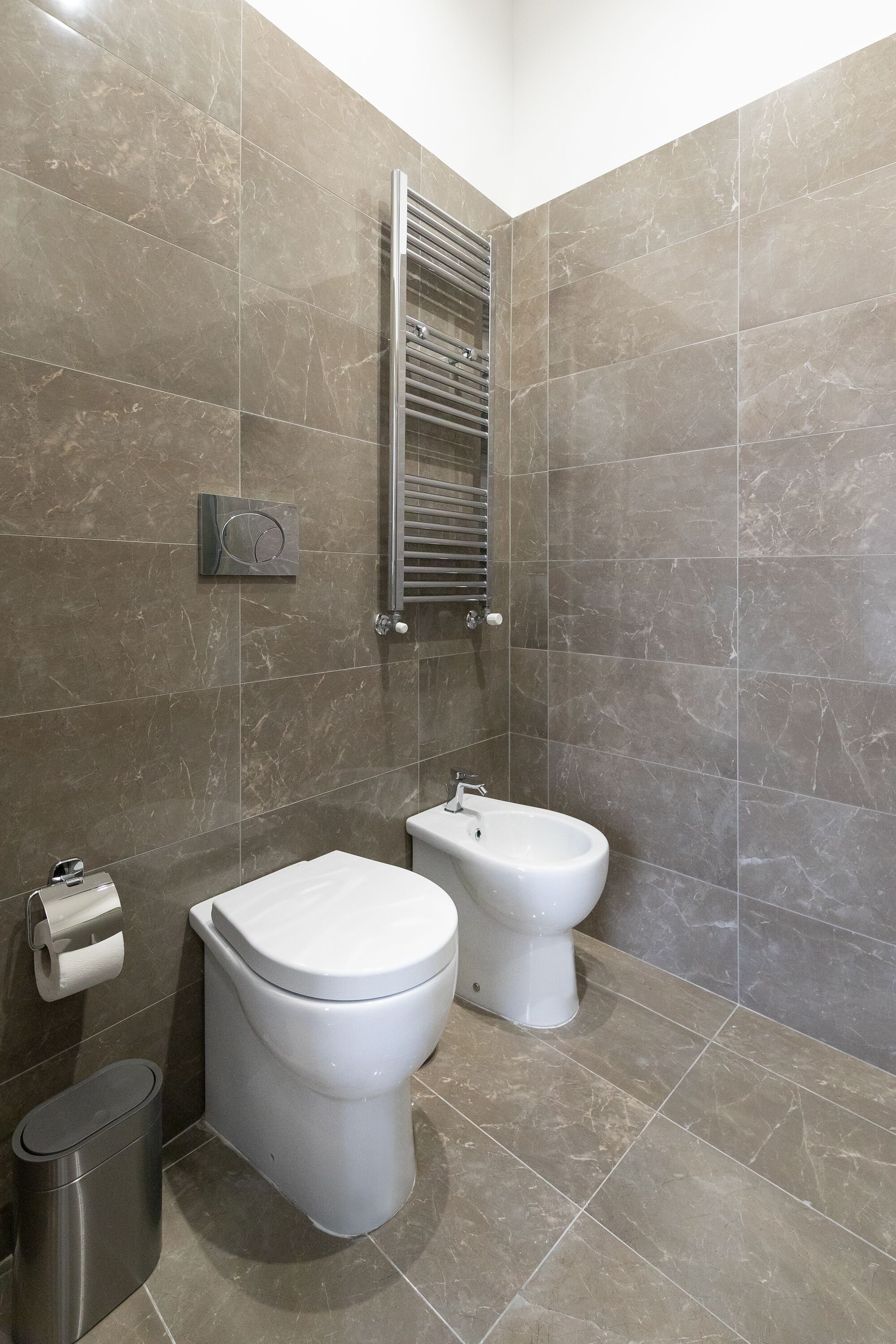 A bathroom with a toilet, bidet, and a trash bin.