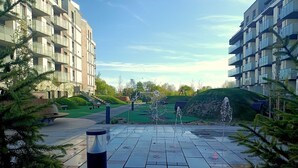 Een binnenplaats met een fontein, een speeltuin en een gebouw met balkons.