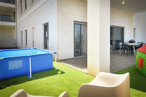 A pool area with a blue pool, a green lawn, and outdoor seating. - Spacious Four Bedroom Holiday (Nahariya)