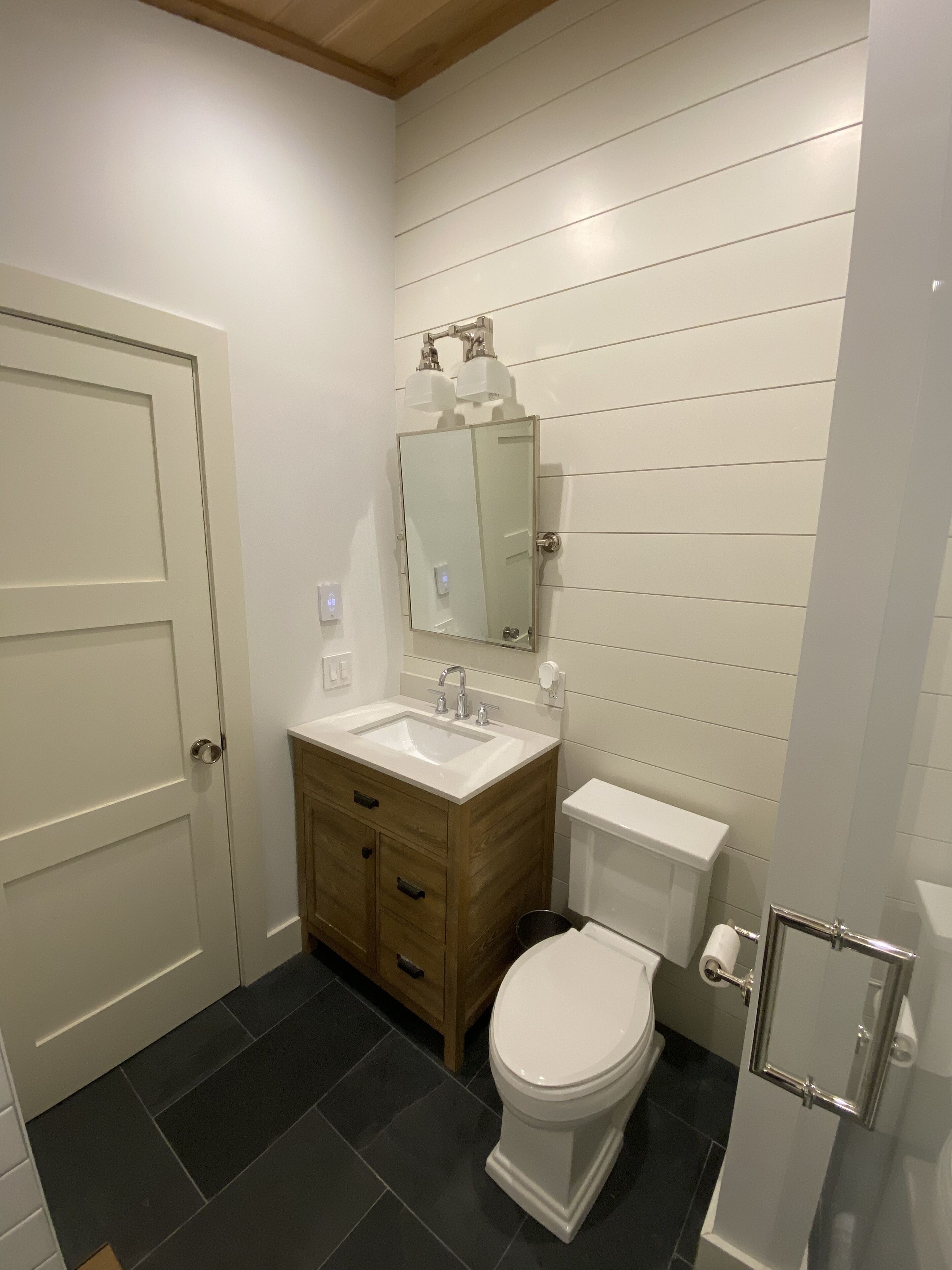 A modern bathroom with a white vanity, a sink, a mirror, and a toilet.